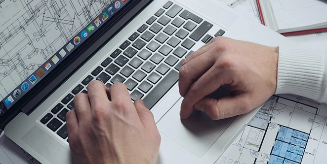 person jobbar med ritningar på laptop